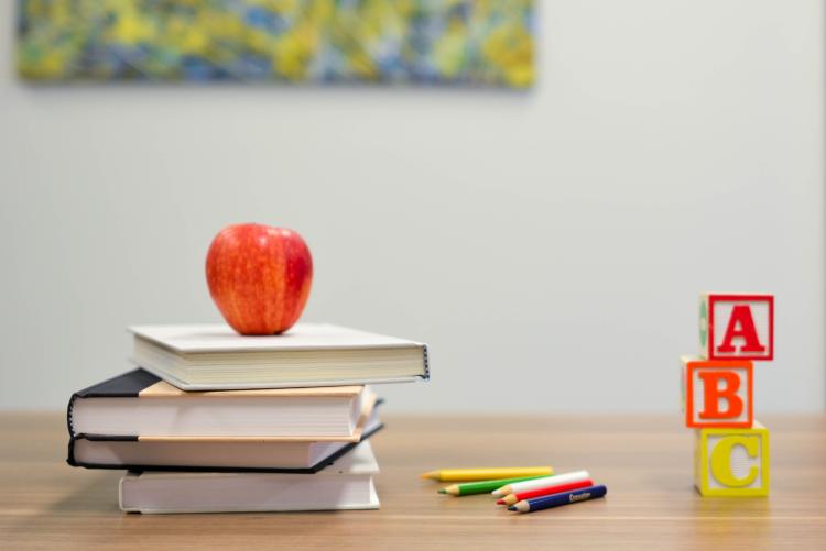 Books stacked with an apple sitting on top
